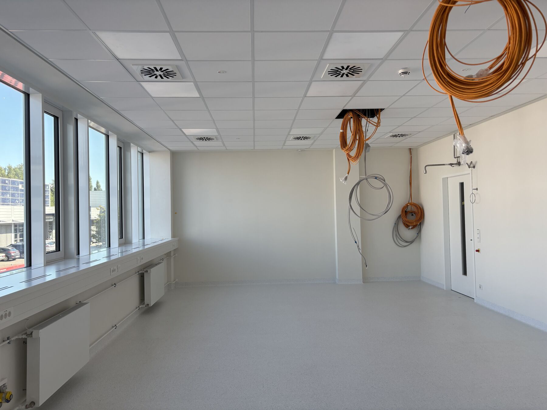 Heller Laborraum mit Fensterfront, Fugenlosem Boden und vorbereiteten Deckenanschlüssen